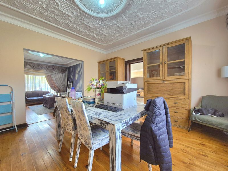 A living area featuring original ornate pressed metal ceilings and warm timber flooring, with built-in timber cabinetry providing storage.