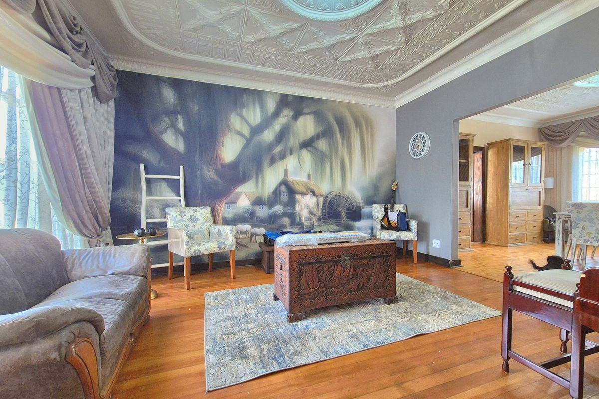 Spacious living room featuring original ornate pressed metal ceilings, a decorative ceiling rose, and polished hardwood flooring.