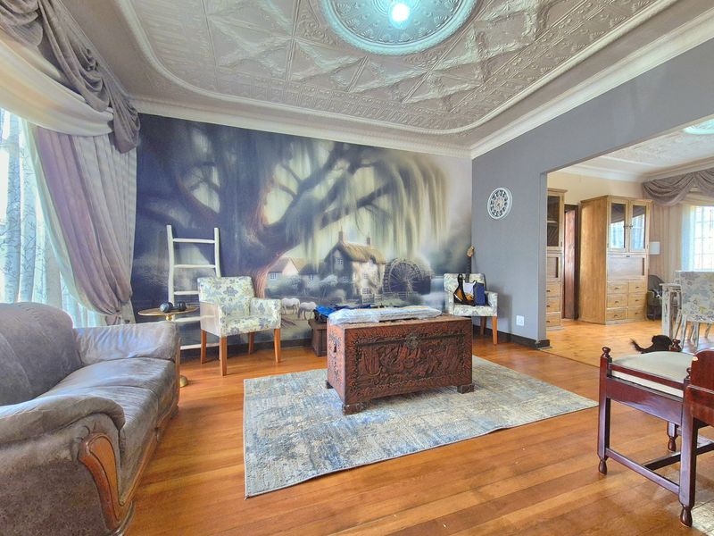 Spacious living room featuring original ornate pressed metal ceilings, a decorative ceiling rose, and polished hardwood flooring.
