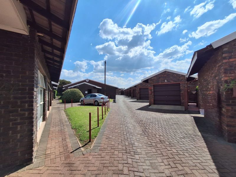 Exterior view of a townhouse complex featuring brick facades, paved driveways, and multiple garage units under a clear sky.