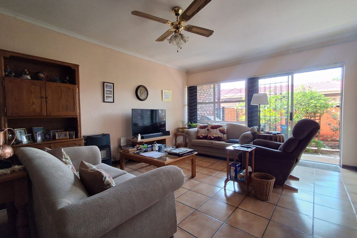 A comfortable living room featuring tiled flooring, a ceiling fan, and large sliding glass doors that provide access to the outdoor area.