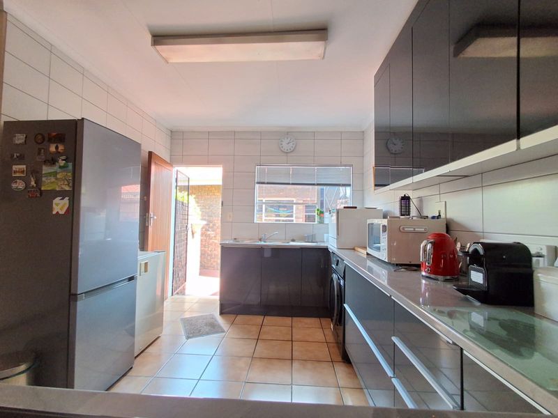 A functional kitchen featuring dark cabinetry, tiled flooring, and a tiled backsplash with direct access to an outdoor area.