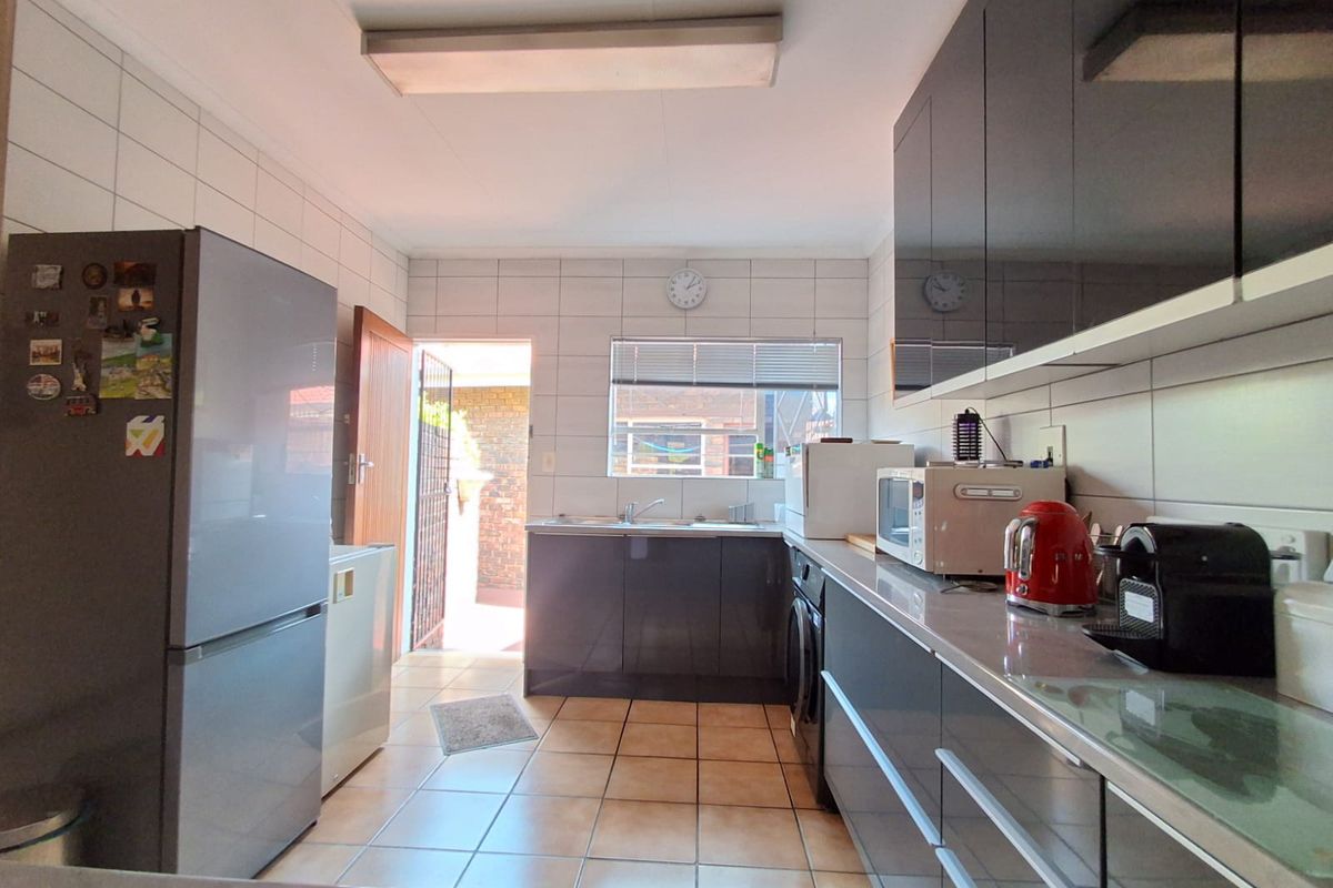 A functional kitchen featuring dark cabinetry, tiled flooring, and a tiled backsplash with direct access to an outdoor area.