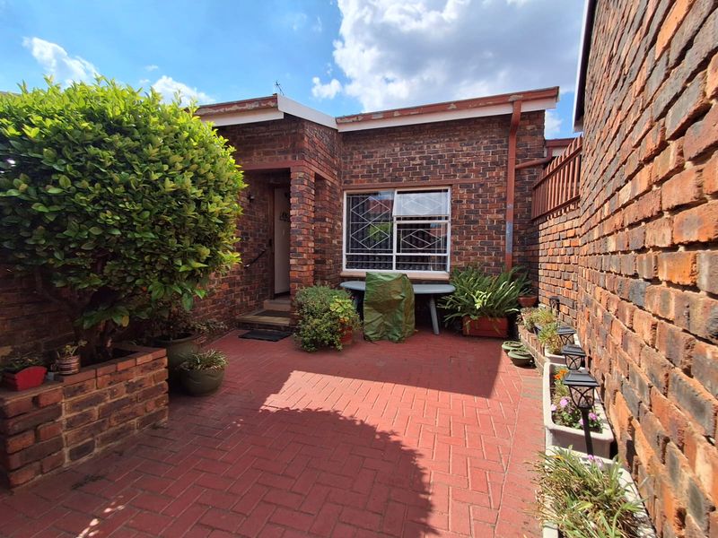 A private rear courtyard featuring red brick paving, facebrick walls, and a built-in planter, providing a low-maintenance outdoor space.