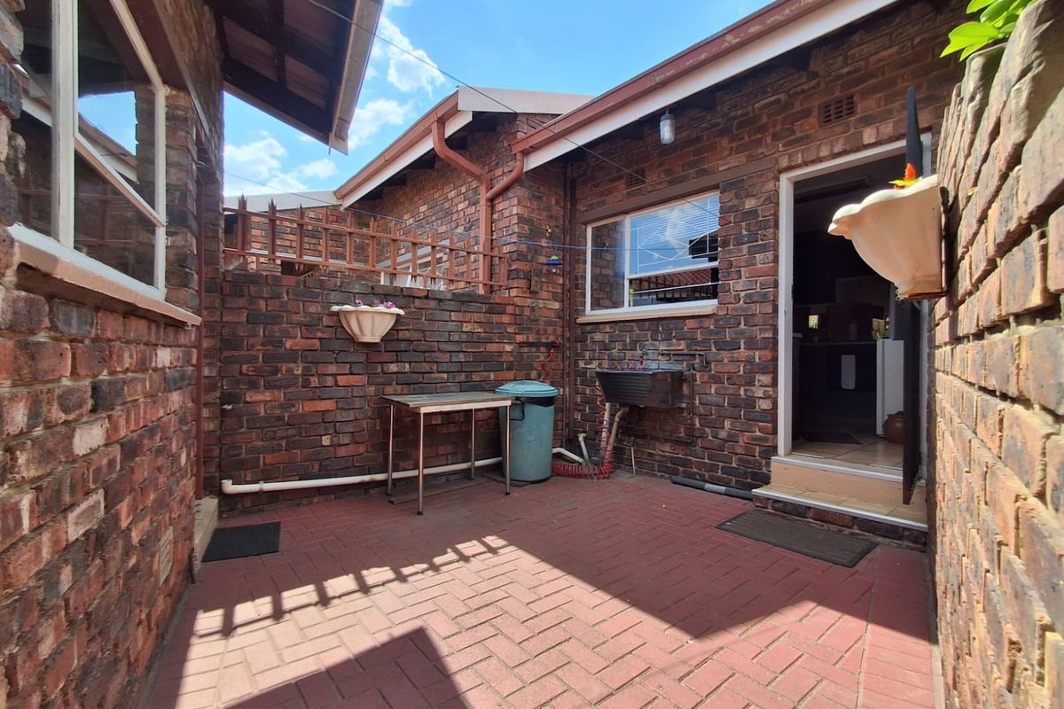 A private rear courtyard featuring durable brick paving, face brick walls, and a functional utility sink area with direct access to the home.
