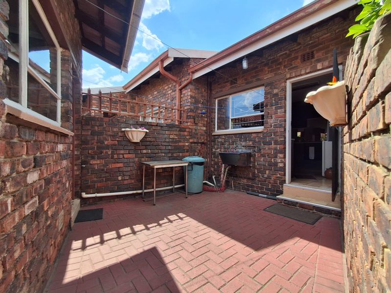 A private rear courtyard featuring durable brick paving, face brick walls, and a functional utility sink area with direct access to the home.