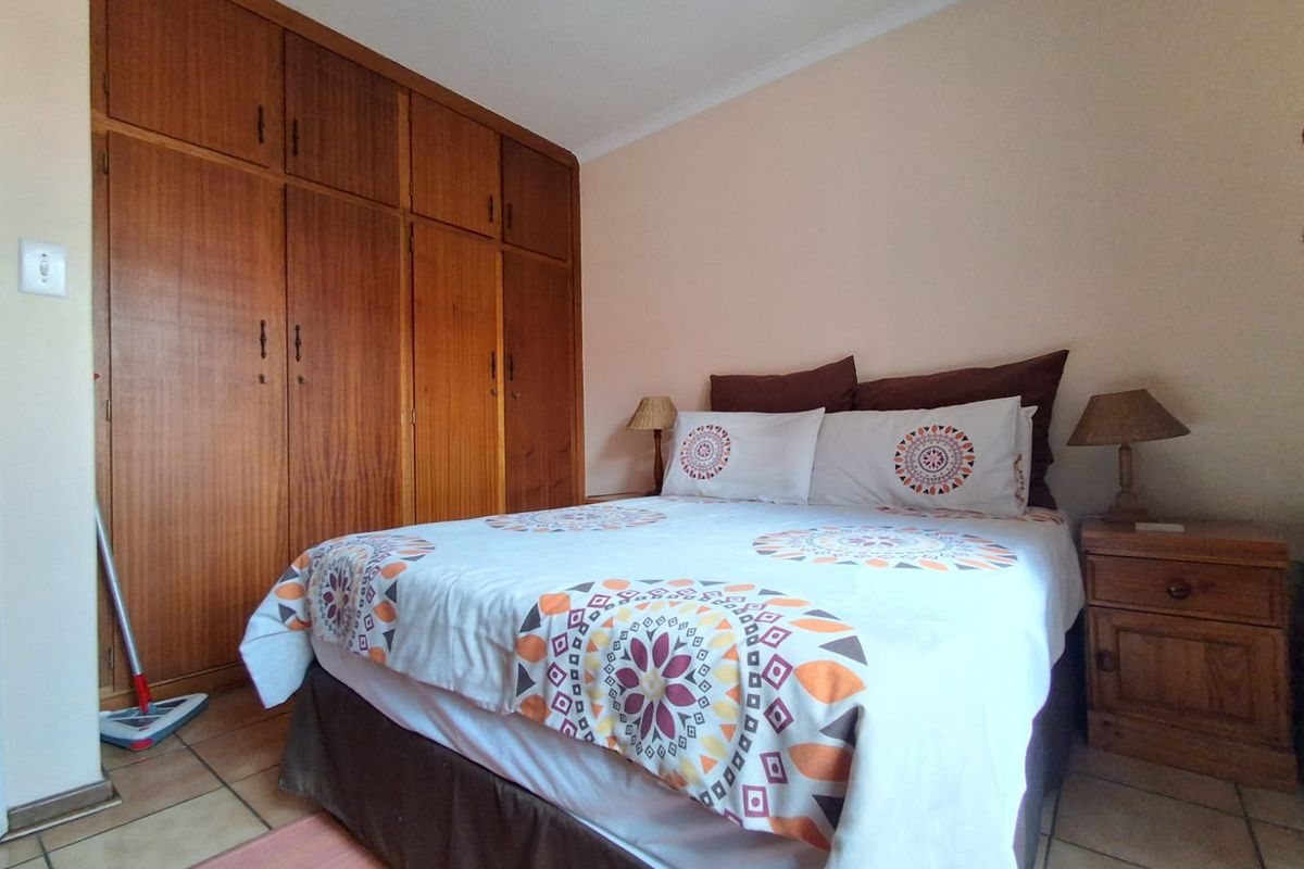 A bedroom featuring built-in wooden cupboards and tiled flooring, offering a functional space with classic cabinetry.