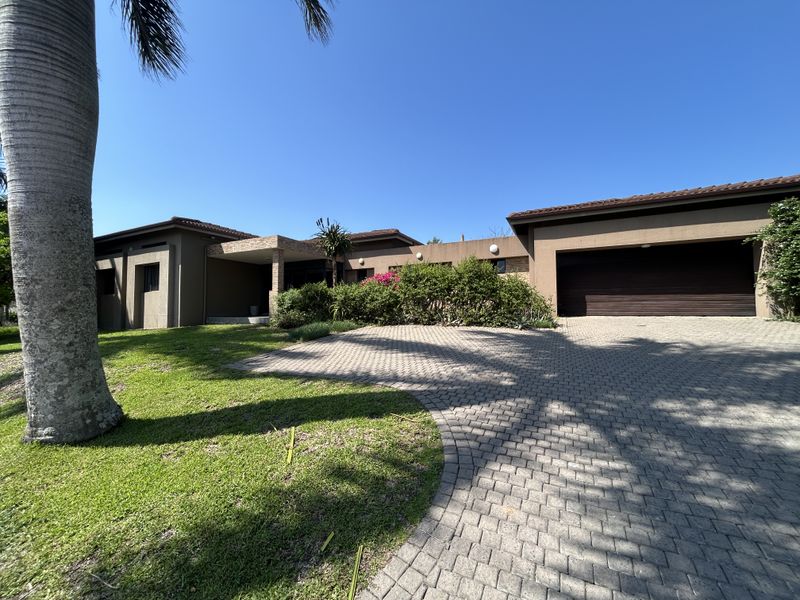Front elevation of a modern house featuring a paved driveway, double garage, and a covered entrance with stone cladding accents.