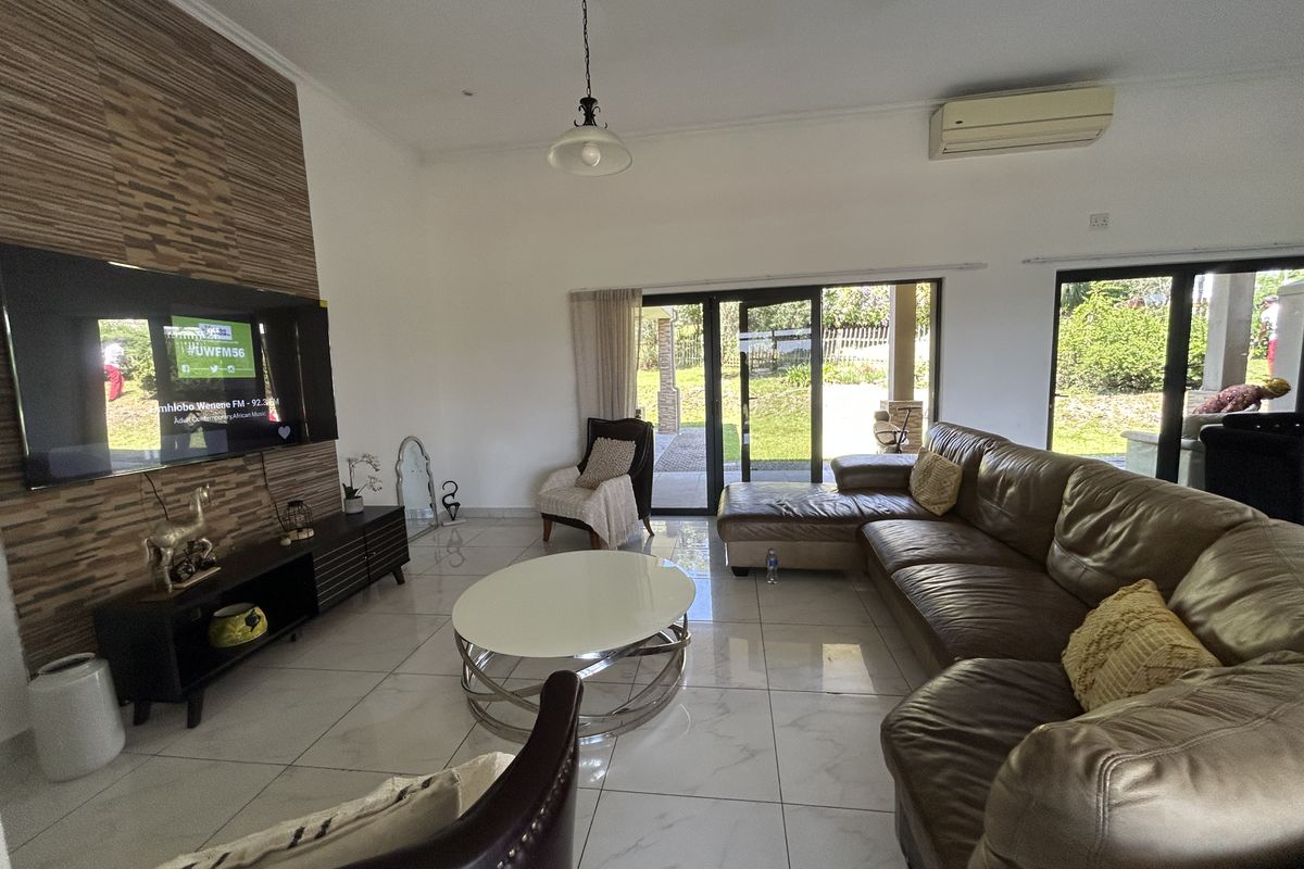 Spacious living room featuring large format floor tiles, a decorative feature wall, and sliding glass doors providing direct access to the outdoor patio area.