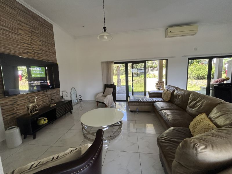 Spacious living room featuring large format floor tiles, a decorative feature wall, and sliding glass doors providing direct access to the outdoor patio area.