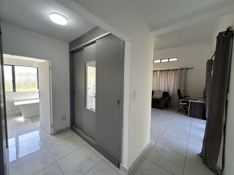 A bright hallway featuring modern white tiled flooring and a built-in sliding door wardrobe, providing access to adjacent rooms.