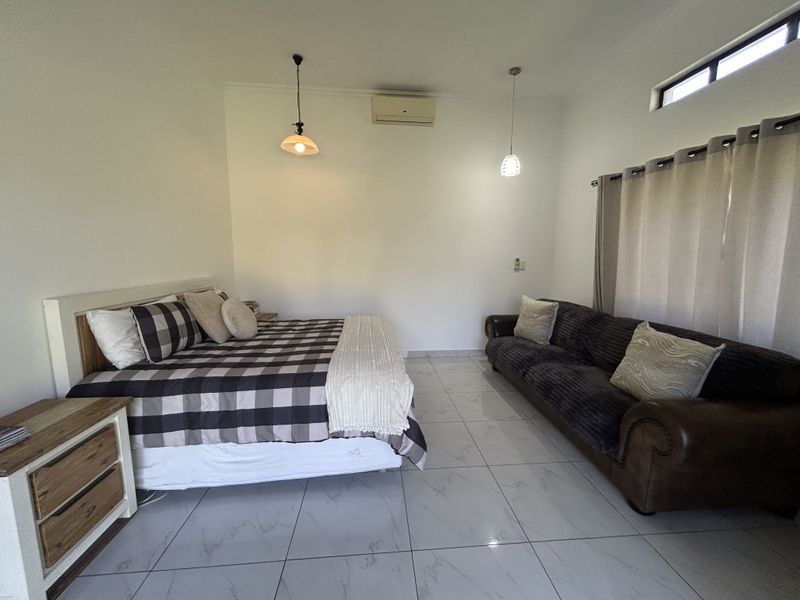 Spacious bedroom featuring modern porcelain floor tiles, split-system air conditioning, and clerestory windows providing natural light.