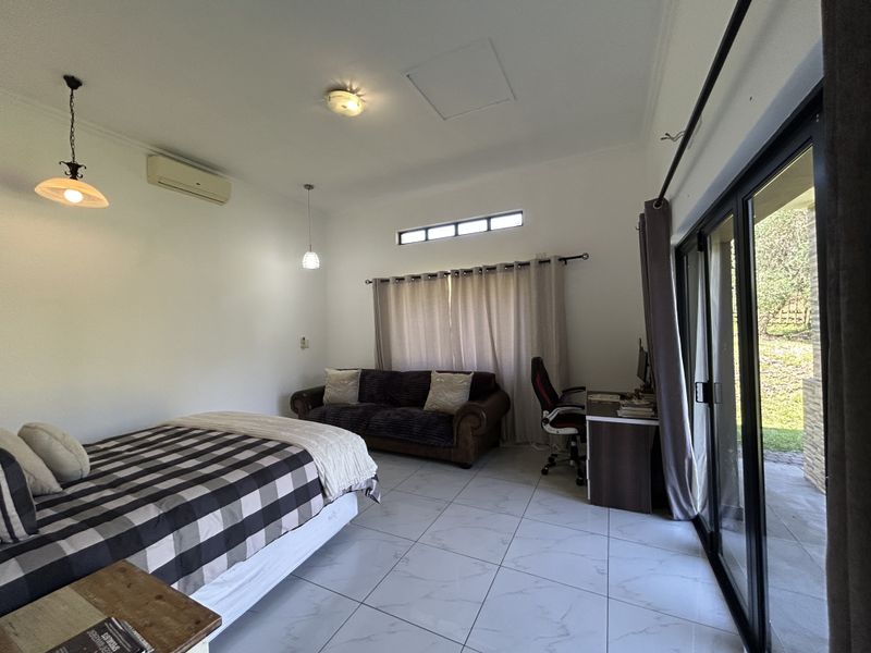 Spacious bedroom featuring tiled flooring, split-system air conditioning, and large sliding glass doors providing direct access to the outdoor area.