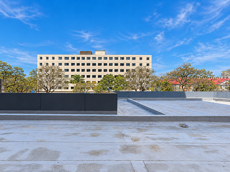 A large, open rooftop terrace area featuring a flat membrane roof and perimeter parapet walls, offering an expansive view of the surrounding urban landscape.