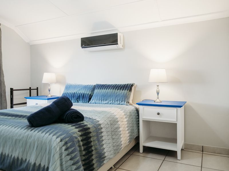 A well-maintained bedroom featuring tiled flooring, a wall-mounted air conditioning unit, and built-in storage.