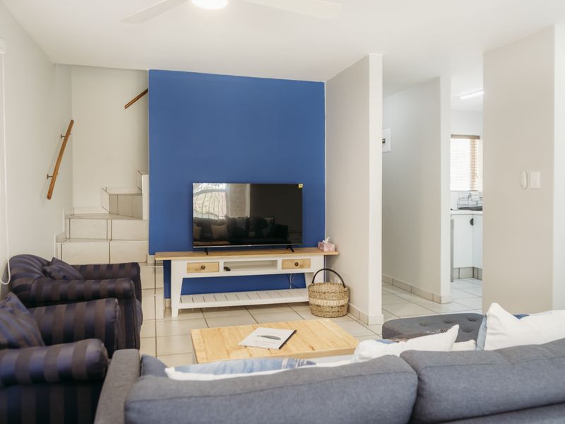 Open plan living area featuring tiled flooring, a staircase with a handrail, and a view through to the kitchen area.