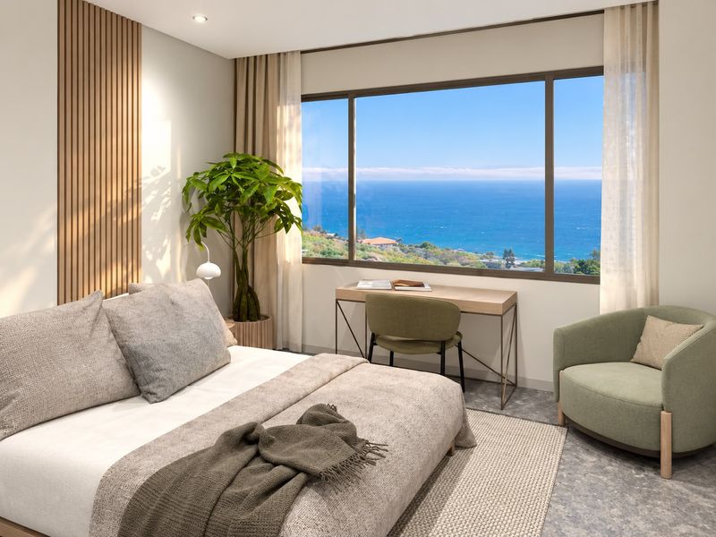A modern, well-appointed bedroom featuring elegant timber slat wall detailing and a large window offering expansive ocean views.