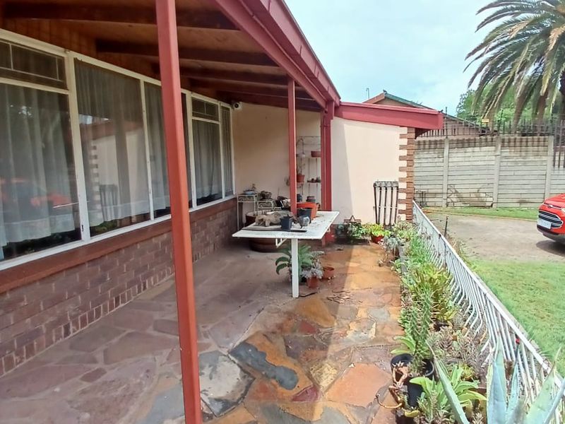 A covered patio area featuring flagstone paving, a timber-lined roof, and a metal railing, providing a functional outdoor space for relaxation.