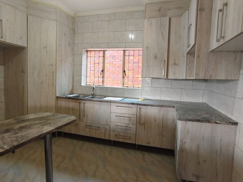 A functional kitchen featuring light wood-look cabinetry, stone-effect countertops, tiled backsplash, and tiled flooring, offering a clean and neutral space ready for personalization.
