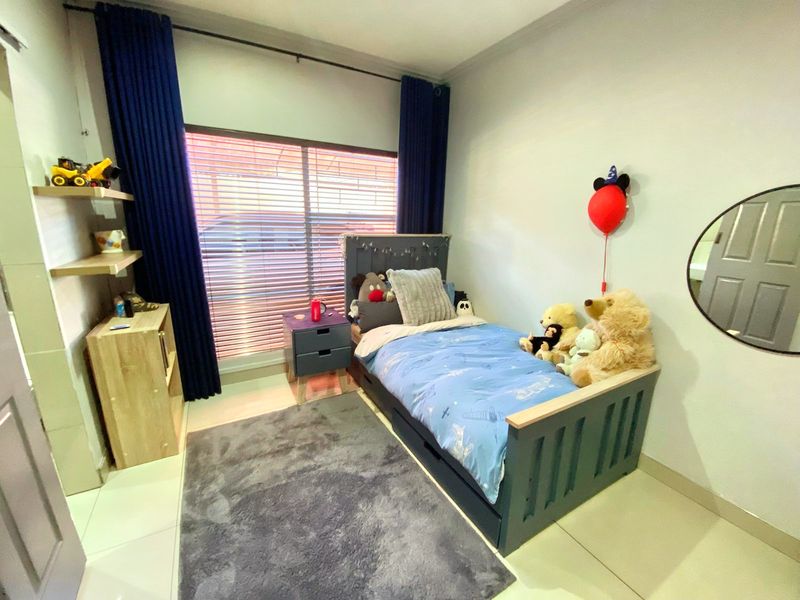 A well-maintained bedroom featuring tiled flooring, built-in shelving units, and window blinds, offering a functional and comfortable living space.