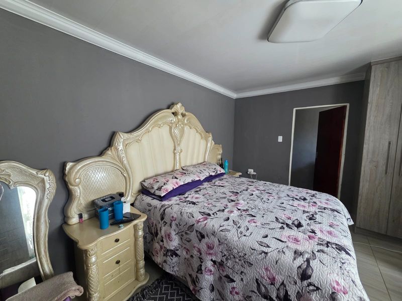 A bedroom featuring grey walls, crown molding, tiled flooring, and a built-in wardrobe.