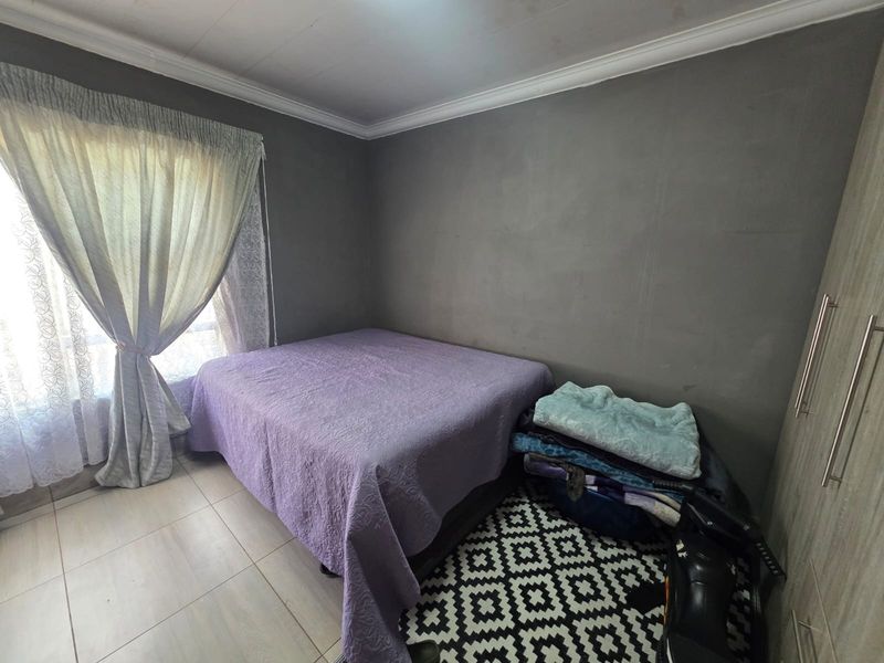 A bedroom featuring tiled flooring, a built-in wardrobe, and neutral grey walls with decorative cornice detailing.