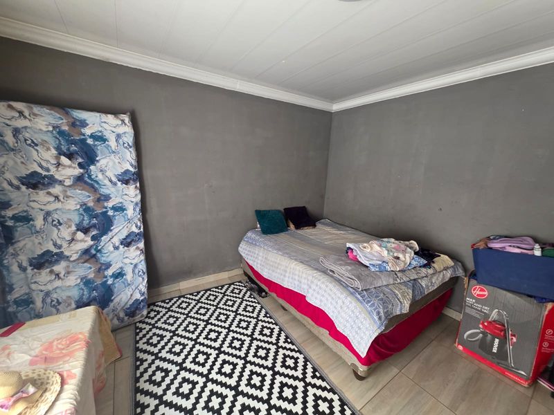 A bedroom featuring tiled flooring and coved ceilings, currently requiring cosmetic updates to the wall finishes to improve the overall aesthetic.
