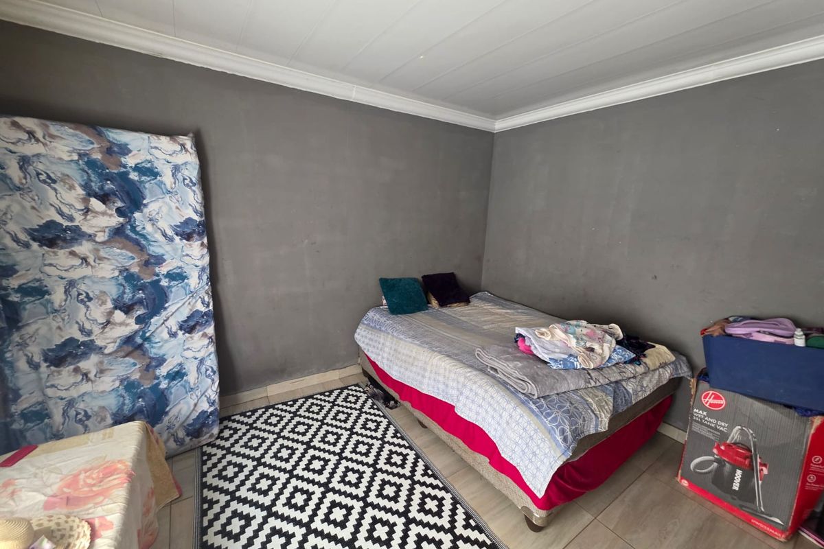 A bedroom featuring tiled flooring and coved ceilings, currently requiring cosmetic updates to the wall finishes to improve the overall aesthetic.