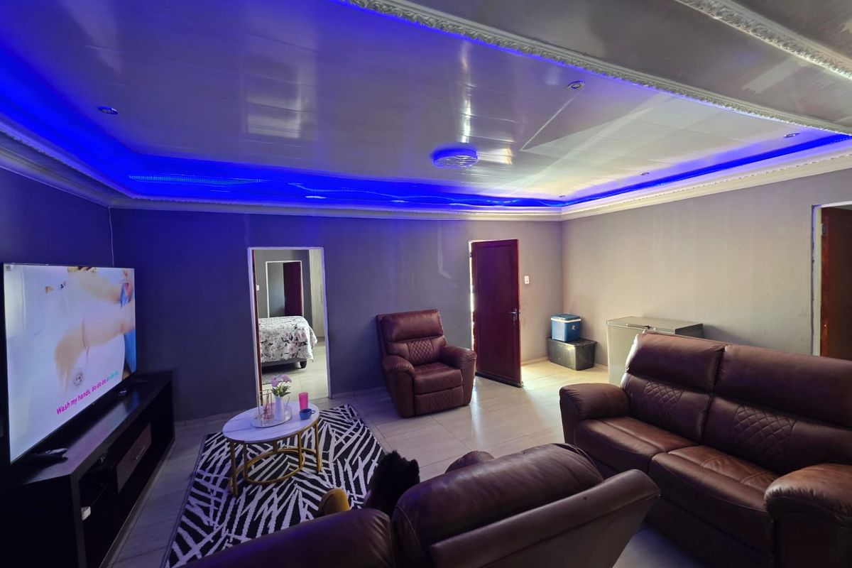Spacious living room featuring a modern recessed ceiling with integrated blue LED lighting and neutral tiled flooring.