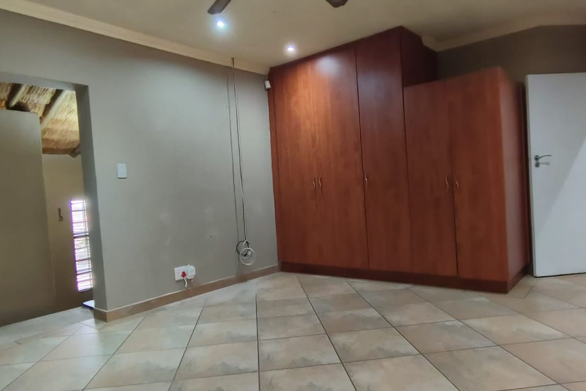 A spacious bedroom featuring tiled flooring, built-in wooden cupboards, and recessed lighting, offering a neutral canvas ready for personalization.