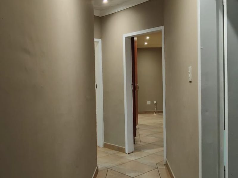 A functional hallway featuring tiled flooring, a tongue and groove ceiling with track lighting, and access to adjacent rooms.
