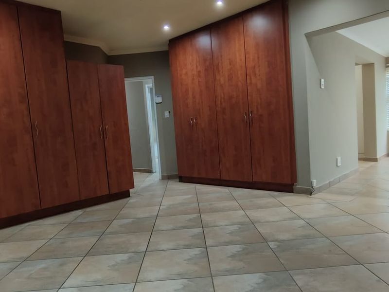 Spacious living area featuring extensive built-in wooden cabinetry, neutral tiled flooring, and recessed lighting, offering a versatile layout for various interior design styles.