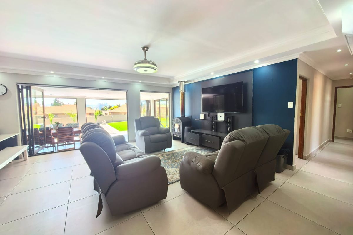 Spacious living room featuring large stacking glass doors, tiled flooring, recessed lighting, and a modern freestanding fireplace, creating a bright and open atmosphere.