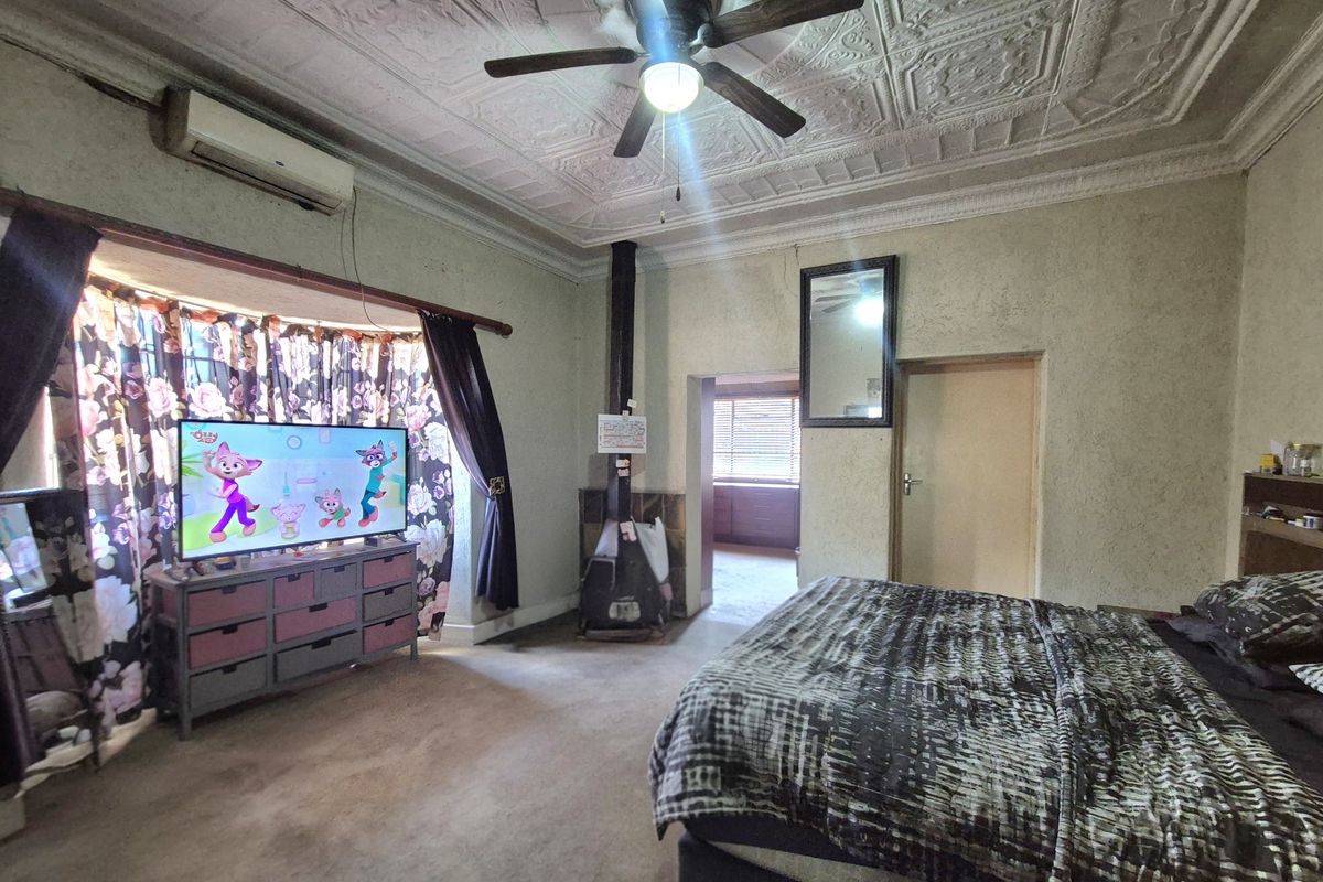 Spacious bedroom featuring a decorative pressed metal ceiling, ceiling fan, wood-burning fireplace, and split-system air conditioning.