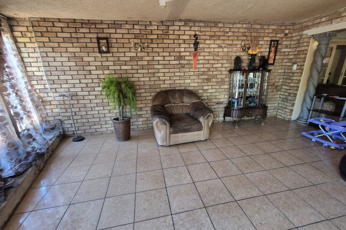Living room featuring exposed brick walls and ceramic floor tiles, requiring some ceiling maintenance and cosmetic updates.