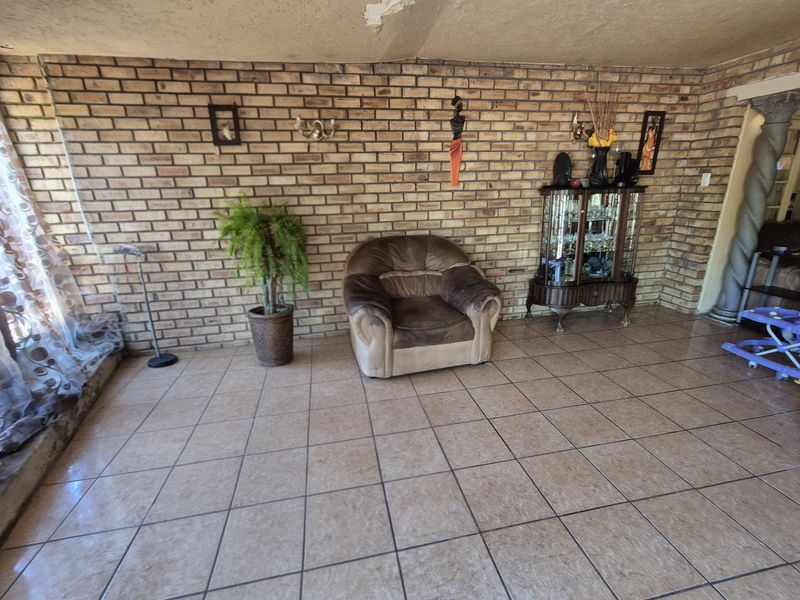 Living room featuring exposed brick walls and ceramic floor tiles, requiring some ceiling maintenance and cosmetic updates.