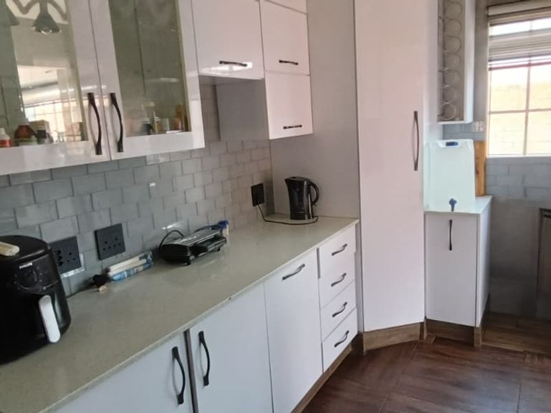 A functional kitchen featuring white cabinetry, quartz countertops, and a subway tile backsplash with wood-look floor tiles.