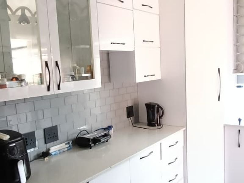Modern kitchen featuring white cabinetry, subway tile backsplash, stone countertops, and dark tiled flooring with stylish pendant lighting.