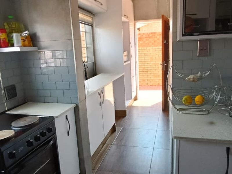 A functional kitchen featuring white cabinetry, stone countertops, subway tile backsplash, and a built-in microwave, with direct access to an outdoor area.