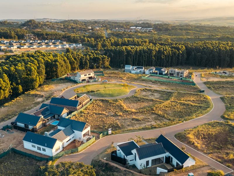 Aerial view of a residential estate development featuring modern homes, paved access roads, and surrounding natural landscape.