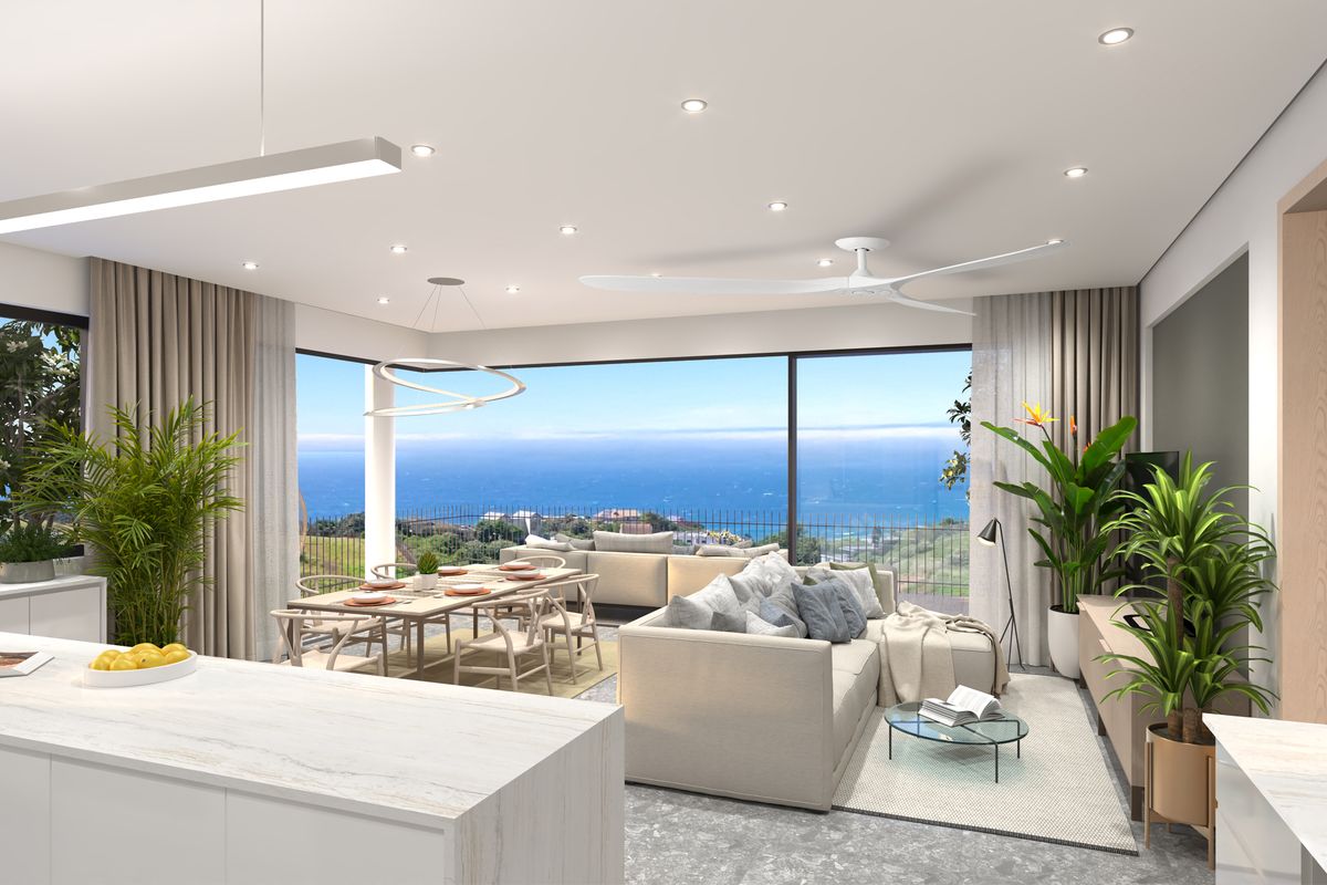 Modern open-plan living and dining area featuring a sleek kitchen island, recessed lighting, and expansive sliding glass doors showcasing panoramic ocean views.