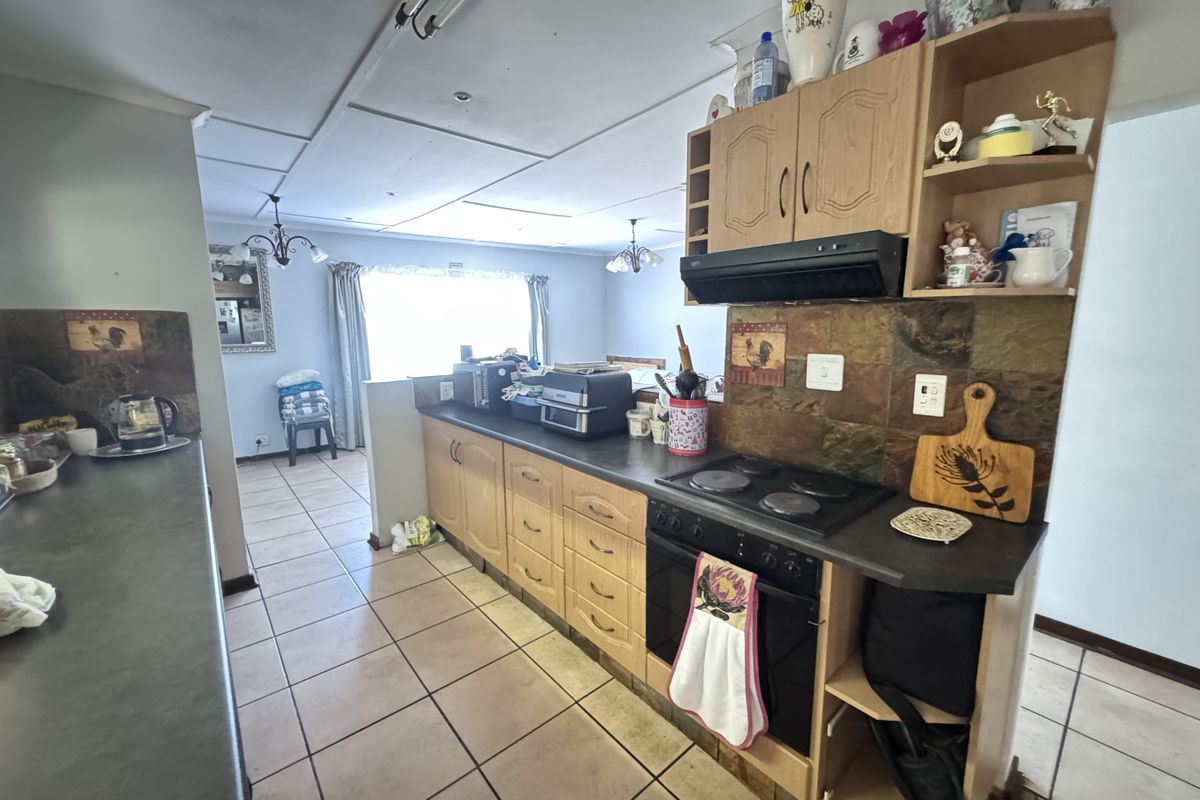 A functional kitchen featuring wooden cabinetry, built-in oven and hob, and tiled flooring, offering potential for modernization and aesthetic updates.