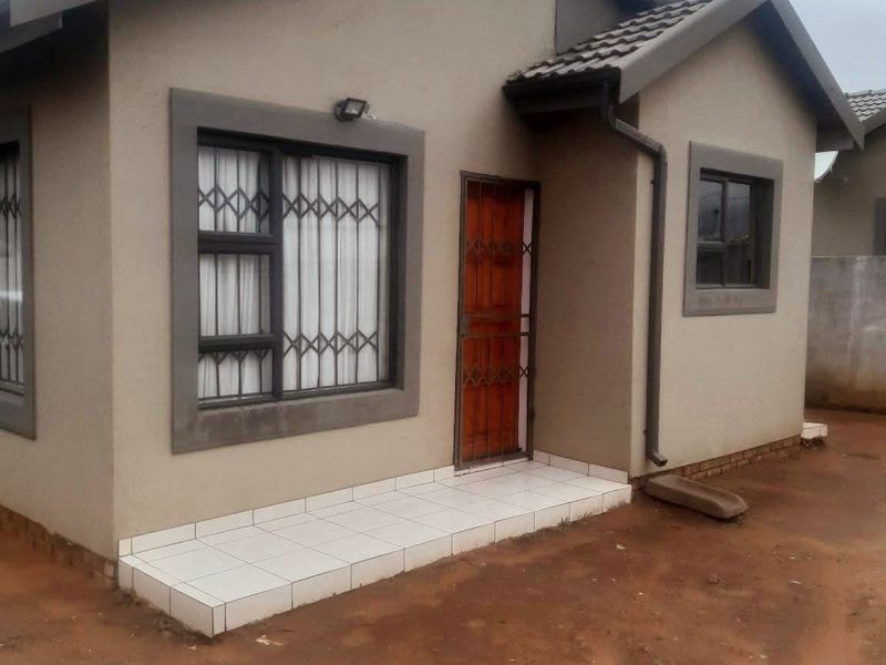 Front elevation of a single-story house featuring a tiled entrance porch, security gates, and aluminium window frames with a neutral exterior finish.