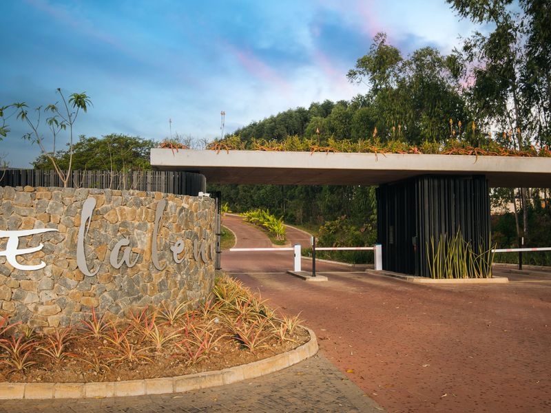 The entrance to the Elaleni estate features a modern concrete canopy, stone-clad signage wall, and a secure boom gate access point.
