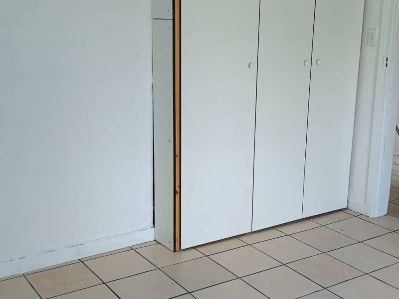 A vacant bedroom featuring neutral ceramic floor tiles and functional built-in storage cupboards.