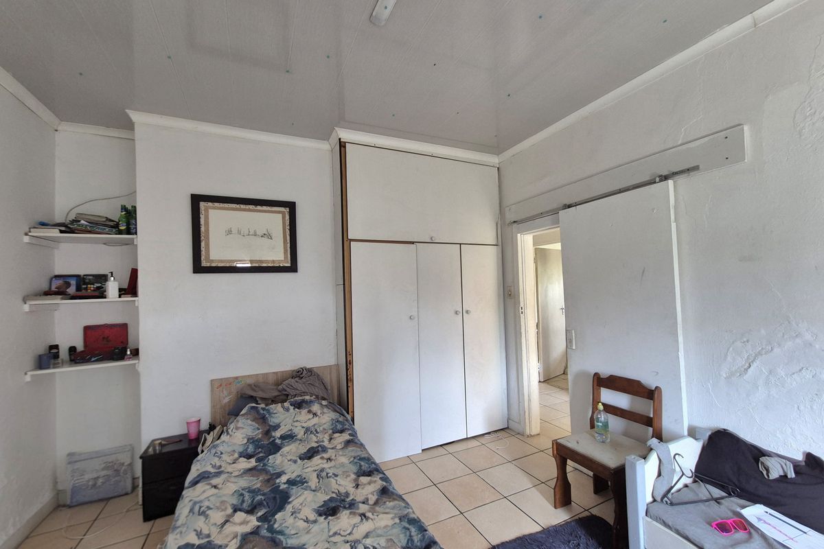 A bedroom featuring built-in cupboards, tiled flooring, and built-in shelving, requiring cosmetic updates to the walls and ceiling.