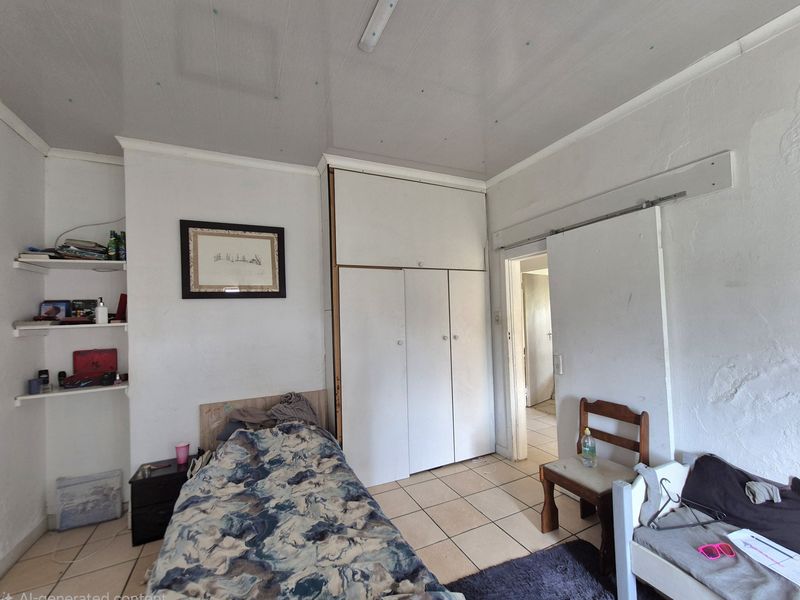 A bedroom featuring built-in cupboards, tiled flooring, and built-in shelving, requiring cosmetic updates to the walls and ceiling.