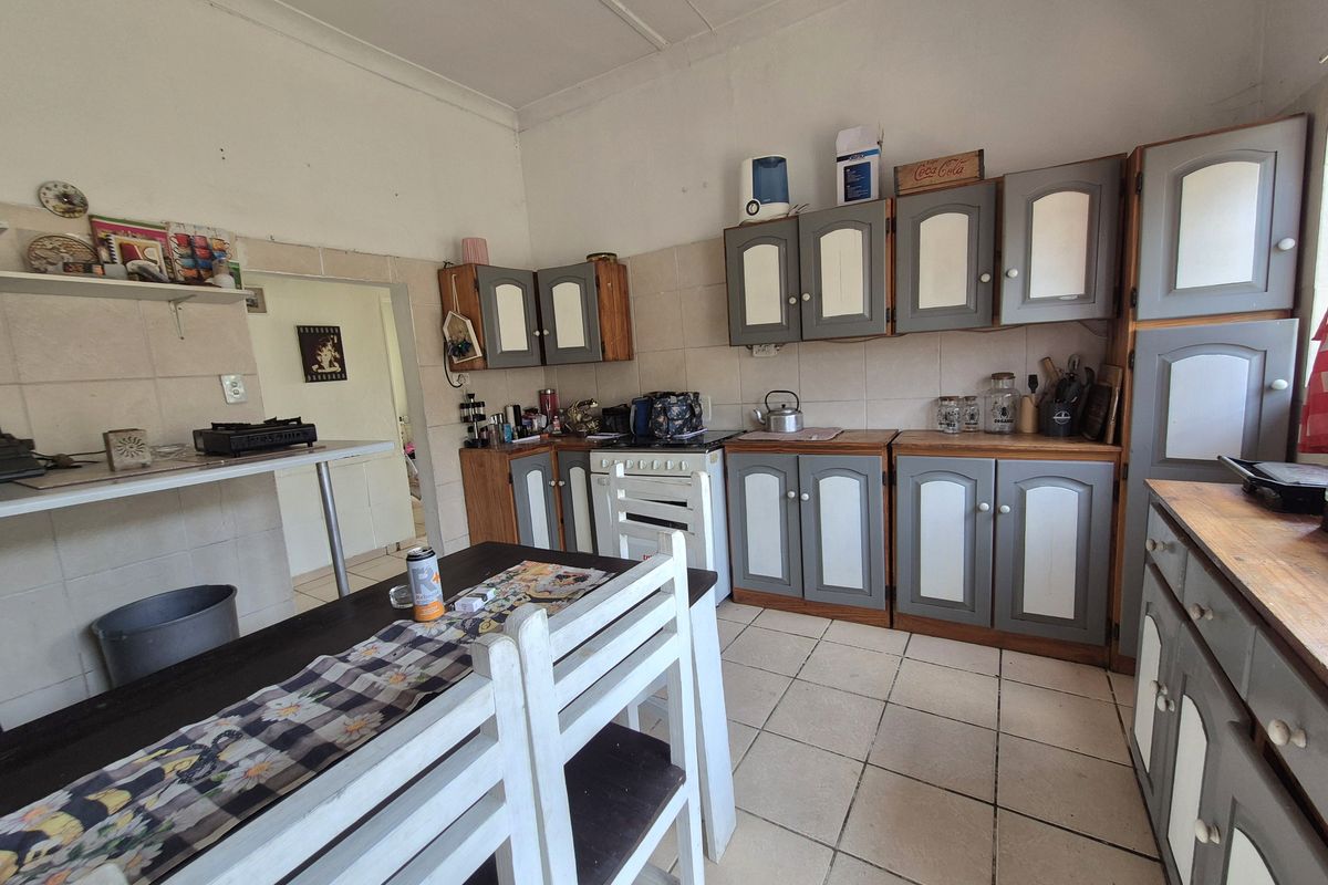 A dated kitchen featuring built-in cabinetry, tiled flooring, and a tiled backsplash, offering significant potential for modernization and renovation.