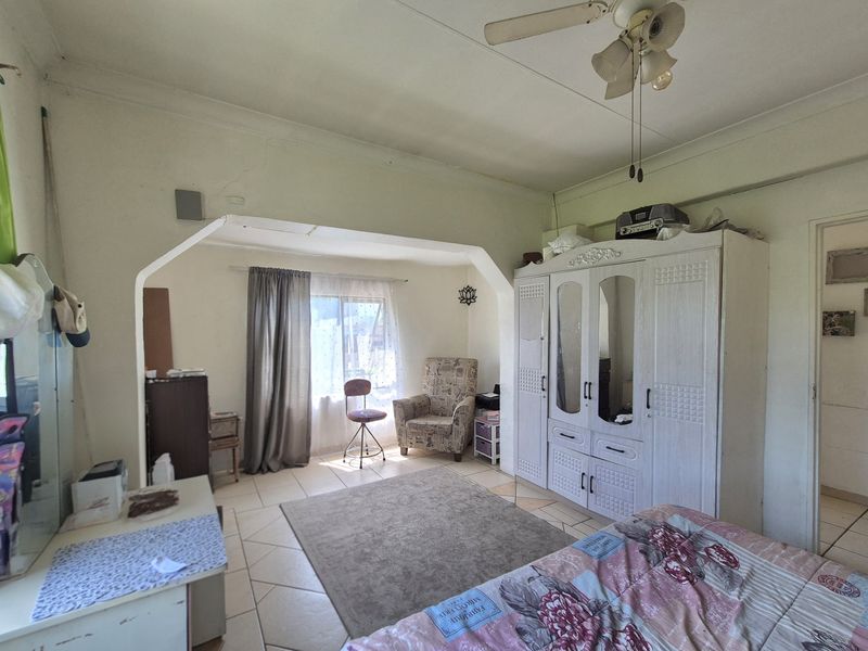 Spacious bedroom featuring tiled flooring, a ceiling fan, and a distinct architectural archway leading to a secondary seating area.