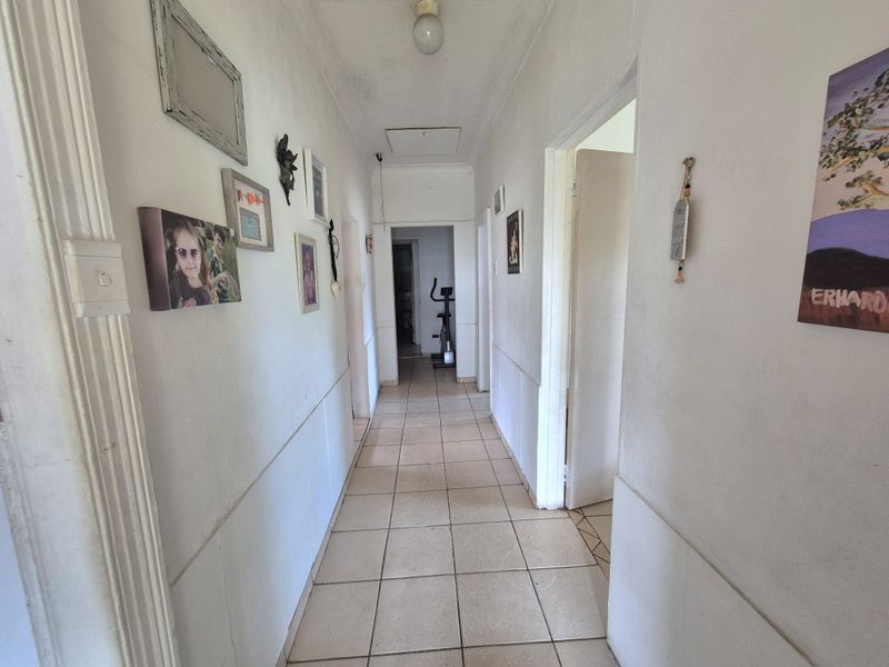 A functional hallway featuring tiled flooring and a ceiling access hatch, providing central access to the various rooms of the home.